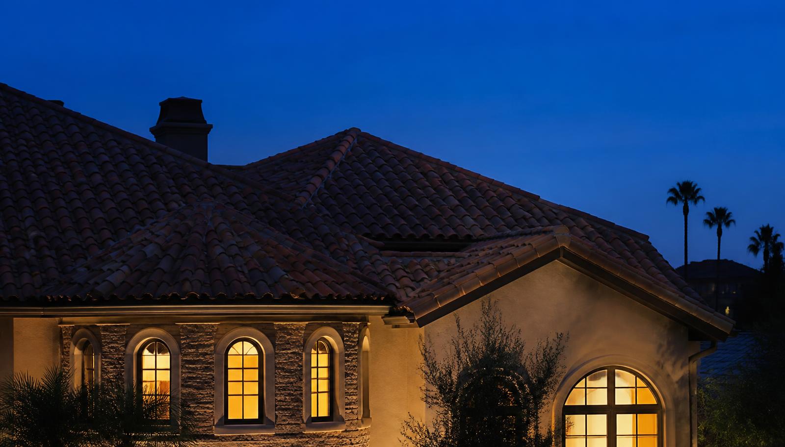 Premium residential tile roof at dusk with warm interior light